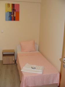 a small bedroom with a bed with a pink blanket at Apartments Georgos in Sofia