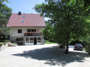 
a white house with a blue roof and a white car parked in front of at Guest House Nenad in Plitvička Jezera
