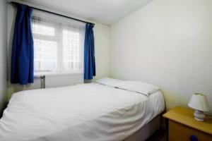 1 dormitorio con 1 cama y una ventana con cortinas azules en Wood Green direct tube Eurostar Heathrow, close Ally Pally, en Londres