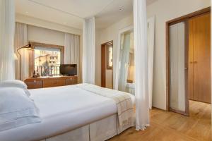Un dormitorio con una gran cama blanca y una ventana en Hotel Continentale - Lungarno Collection, en Florencia