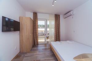 1 dormitorio con 1 cama y TV en la pared en Apartmani "Nebo" en Sutomore
