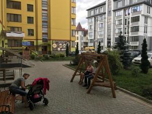 a group of people sitting in a park with a swing at VIP Apartament in the center in Truskavets