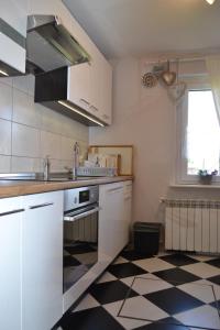a kitchen with white cabinets and a black and white checkered floor at Dom u Ewy Bory Tucholskie in Śliwice +24 photos