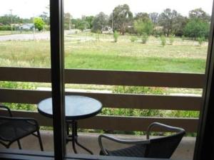a table and chairs on a balcony with a view of a field at Red Cedars Motel in Canberra