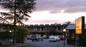 un parcheggio con auto parcheggiate di fronte a un edificio di Red Cedars Motel a Canberra