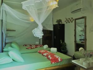 a bedroom with two beds with red and white pillows at Garden Cottage Arugambay in Arugam Bay