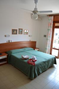 a bedroom with a green bed with two shoes on it at Hotel Berna in Eraclea Mare