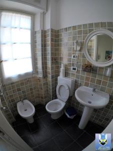 a bathroom with a toilet and a sink and a mirror at Hotel Mimosa in Spotorno
