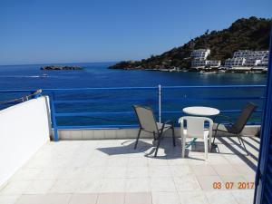 a balcony with a table and chairs overlooking the water at Scirocco Rooms in Loutro