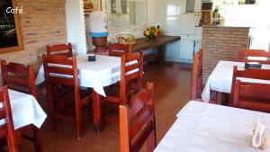 un restaurante con mesas y sillas blancas y una cocina en Pousada Portal, en Chapada dos Guimarães