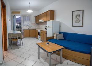 a living room with a blue couch and a kitchen at Pantheon Deluxe Apartments in Archangelos