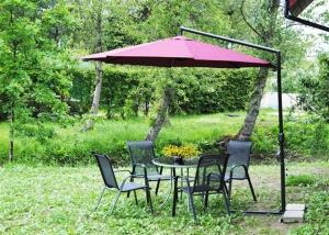 a table and chairs under a red umbrella at Villa Medeina in Šventoji