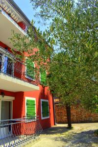 ein rotes Haus mit einem Baum davor in der Unterkunft Apartments Matulic in Zadar