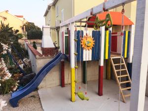a playground in front of a house with a slide at Apartments Villa Dolmar in Vodice