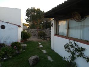 a garden next to a white building with a stone wall at B&B Codduecchju in Arzachena