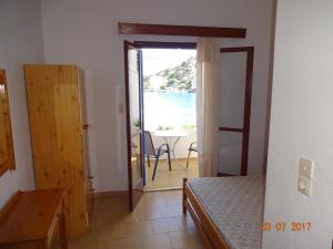 a bedroom with a door open to a view of the ocean at Scirocco Rooms in Loutro