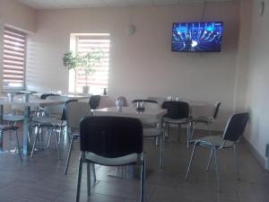 a dining room with tables and chairs and a tv on the wall at zajazd ''Marcówka" in Bakałarzewo