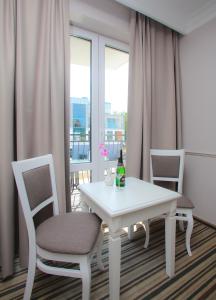 a white table and chairs in a room with windows at Willa Aura Mare in Dziwnów