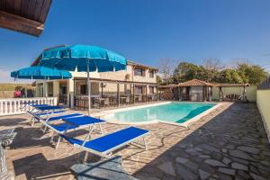 a pool with blue lounge chairs and an umbrella at Villa Gengi in Ardea