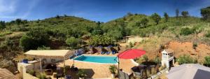 um resort com uma piscina e um guarda-sol vermelho em Terra das Delicias em Morenos