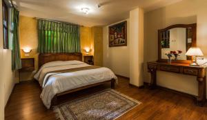 Schlafzimmer mit einem Bett, einem Tisch und einem Spiegel in der Unterkunft Hotel San Francisco De Quito in Quito