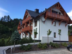 a white building with wooden balconies on it at Apartament Danusia in Szczawnica