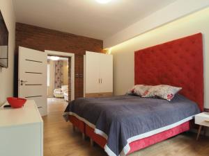 a bedroom with a large bed with a red headboard at Grand Tourist Simple Rest Apartments in Gdańsk
