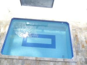 a swimming pool with blue tiles on the side of a building at Pousada Olga in Praia Grande