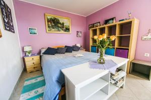 1 dormitorio con 1 cama y un jarrón de flores sobre una mesa en Cozy Istrian House en Izola