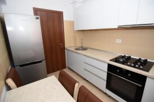 ママイア・ノルドにあるMusic Apartment Mamaia Nordの小さなキッチン(コンロ、冷蔵庫付)