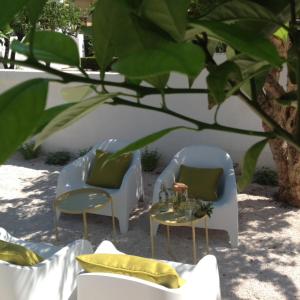 two chairs and a table under a tree at Corte dei melograni-Suite familiare-zona Ostuni in Montalbano