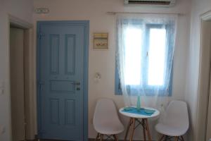 a room with a blue door and a table and chairs at Studios Betty in Plaka Milou