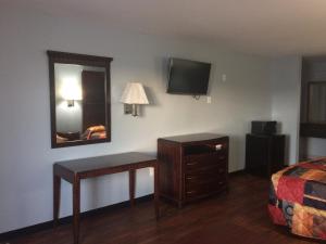 1 dormitorio con escritorio, espejo y cama en Gulf American Inns en Decatur