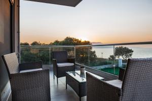 a balcony with chairs and a table and a view of the ocean at Niovi Seaside Suites in Kissamos