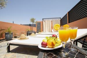 una mesa con un plato de fruta y dos vasos de zumo de naranja en Riad 64 Maison D'hôtes & Spa, en Marrakech