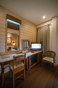 a room with a desk with a television and a mirror at Pukha Nanfa Hotel in Nan