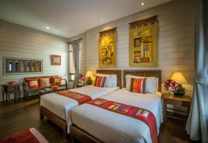 1 dormitorio con 2 camas, mesa y sillas en Pukha Nanfa Hotel en Nan