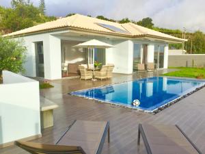 a swimming pool in front of a house at Villa Pinheira III heated pool in Calheta