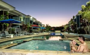 a man and woman sitting next to a swimming pool at Ramada by Wyndham Hervey Bay in Hervey Bay +13 photos