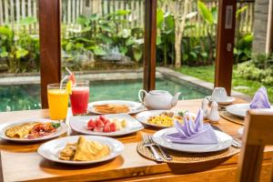 a table with plates of food and drinks on it at Laba Ubud Villa in Ubud