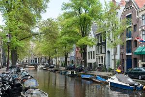 a canal in a city with boats and buildings at Artis Plantage Apartment in Amsterdam