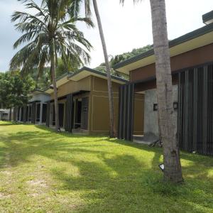 a row of houses with palm trees in the yard at Needa Rock Resort in Khanom