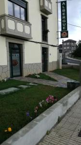 ein Gebäude mit einem Rasen mit Blumen davor in der Unterkunft Albergue Pension Porta Santa in Baleira