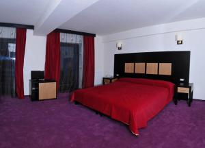 a bedroom with a red bed and red curtains at Hotel ToacaBellevue in Gura Humorului +44 photos