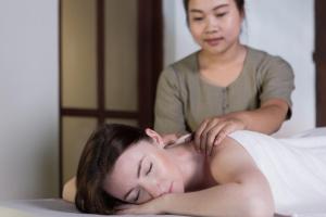 Una mujer recibiendo un masaje de una mujer acostada en una cama en Maison Dalabua, en Luang Prabang