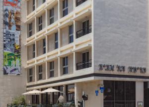 a hotel building with umbrellas in front of it at Prima Tel Aviv Hotel in Tel Aviv