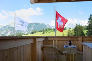 einen Balkon mit zwei Flaggen, einem Tisch und einem Stuhl in der Unterkunft Rinderberg Swiss Alpine Lodge in Zweisimmen