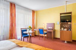 a hotel room with a bed and a table and chairs at Novum Hotel Rega Stuttgart in Stuttgart