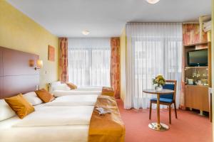 a hotel room with two beds and a table at Hotel Rega Stuttgart in Stuttgart +37 photos