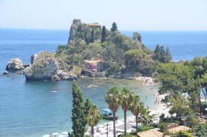 a beach with palm trees and a rocky island at Gole dell'Alcantara Villa Lucia II in Motta Camastra +27 photos